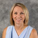 Sally Sorenson, Assistant Director of the Financial Aid Department, stands in front of gray background.