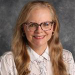 Sara Edwards, Associate Professor for the Legal Studies Department, stands against grey background.