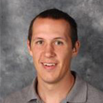 Scott Abbey, Information Technology Professional for the Information Technology Services Department, poses in front of a gray textured background.