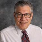Shawn Stafford, Assistant Professor of the Religion Department, poses in front of a gray mottled background at Bethany Lutheran College.