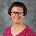 Terri Fries, Clerk for the Spirit Shop, against gray background.