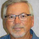 Thomas Hunter, Adjunct Faculty for the Education Department, standing against a grey background