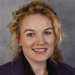Tiffany Young Klockziem, Professor of Health & Human Performance for the Exercise Science Department, smiles against a gray background.
