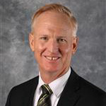 Tim Hartwig, President of the Seminary Department, poses in front of a gray background at Bethany Lutheran College.