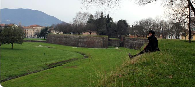 Ruth Wels sitting on a green hillside in Italy