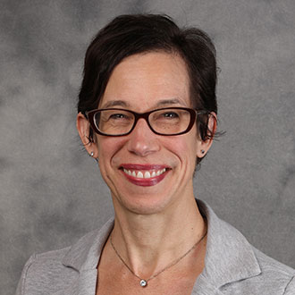 Bethel Balge, Lessons Instructor for the Music Department, smiles against a gray background.