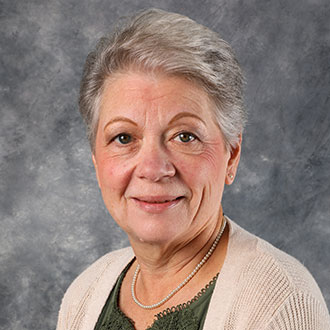 Joni Bode, Data Specialist for the Advancement Department, posed in front of a gray background.