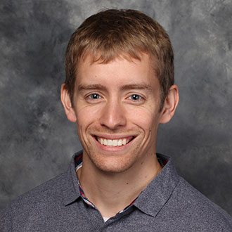 Nick Cook, Director of International Partnerships for the Admissions Department, in front of a gray mottled background.