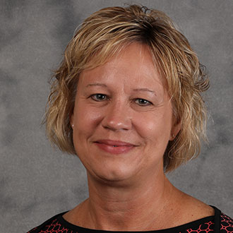 Barb Dressen, Executive Assistant of the President's Office Department, poses in front of a gray background.