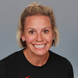 Laura Evans, Head Coach Volleyball and SFC Office Admin for the Athletics Department, standing in front of a black backdrop.