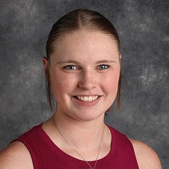 Kristen Flathers, Counselor for the Admissions Department, smiles in front of a gray mottled background.