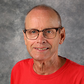 Will Holt, Housekeeping Technician for the Housekeeping Department, in front of a gray mottled background.