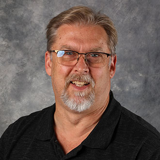 Pat Hull, Director of Facilities of the Facilities Department, posed against a gray mottled background.