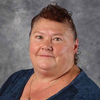 Wanda Hull, Housekeeping Technician for the Housekeeping Department, posing in front of a gray background.