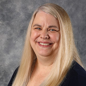Julie Kjeer, Dean of Faculty for the Academic Affairs Department, in front of a gray mottled background.
