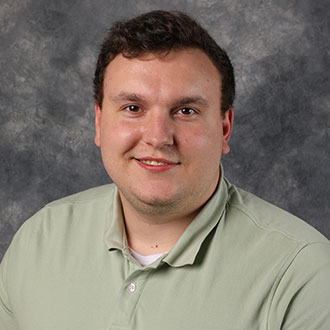 Nicholas Lewison, Resident Hall Coordinator for the Residential Life Department, standing in front of a gray mottled background.