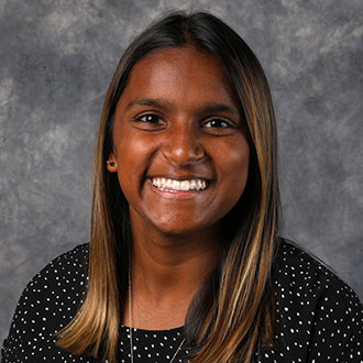Mara Nerland, Resident Hall Coordinator for the Residential Life Department, poses in front of a gray mottled background.