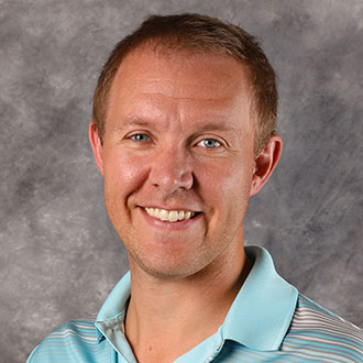 Ben Petzel, Senior Admissions Counselor of the Admissions Department, is positioned in front of a gray mottled background.