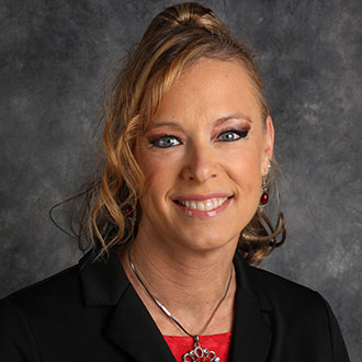 Angie Phares, Director of Career Development for the Career Services Department, smiles in front of a gray mottled background.