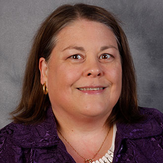 Anita Smith, Adjunct Faculty of the Clinical Mental Health Counseling - Graduate Programs Department, smiles in front of a gray background.