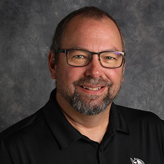 Brian Strom, Head Housekeeper of the Housekeeping Department, poses in front of a gray mottled background.