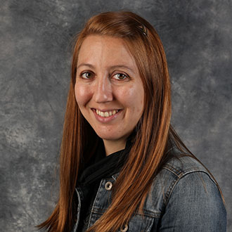 Renee Tatge, Registrar of the Registrar's Office Department, posed in front of a mottled gray studio background.