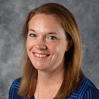 Becca Vance, Nursing Academic Support Specialist of the Nursing Department, stands in front of a gray marbled background.