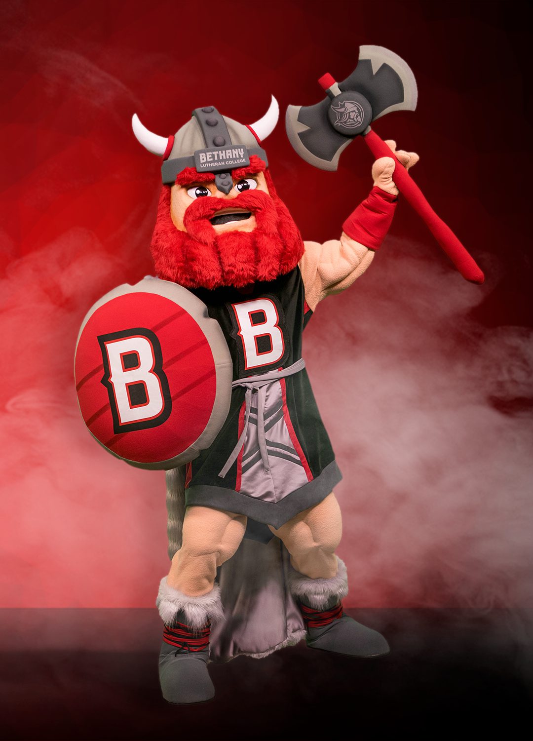 A Viking mascot holding a B emblazoned axe and shield stands against a smoky red background, representing Bethany Lutheran College in Minnesota.