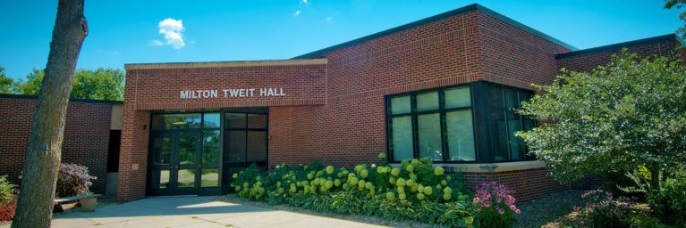 Exterior view of Milton Tweit Hall at Bethany Lutheran College, a brick building with large windows surrounded by Minnesota’s greenery.