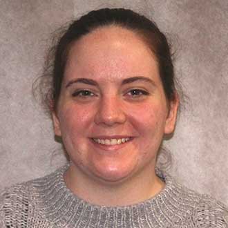 Amber Van Kampen, library Patron Services Coordinator, pictured on grey background